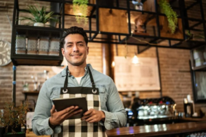 Male shop owner wearing an apron and holding a tablet