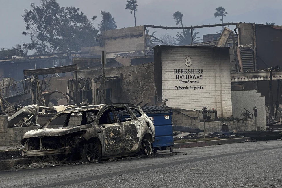 Fire-ravaged businesses and vehicles are left behind after the Palisades Fire swept through in the Pacific Palisades neighborhood of Los Angeles, Wednesday, Jan. 8, 2025. (AP Photo/Eugene Garcia, File)